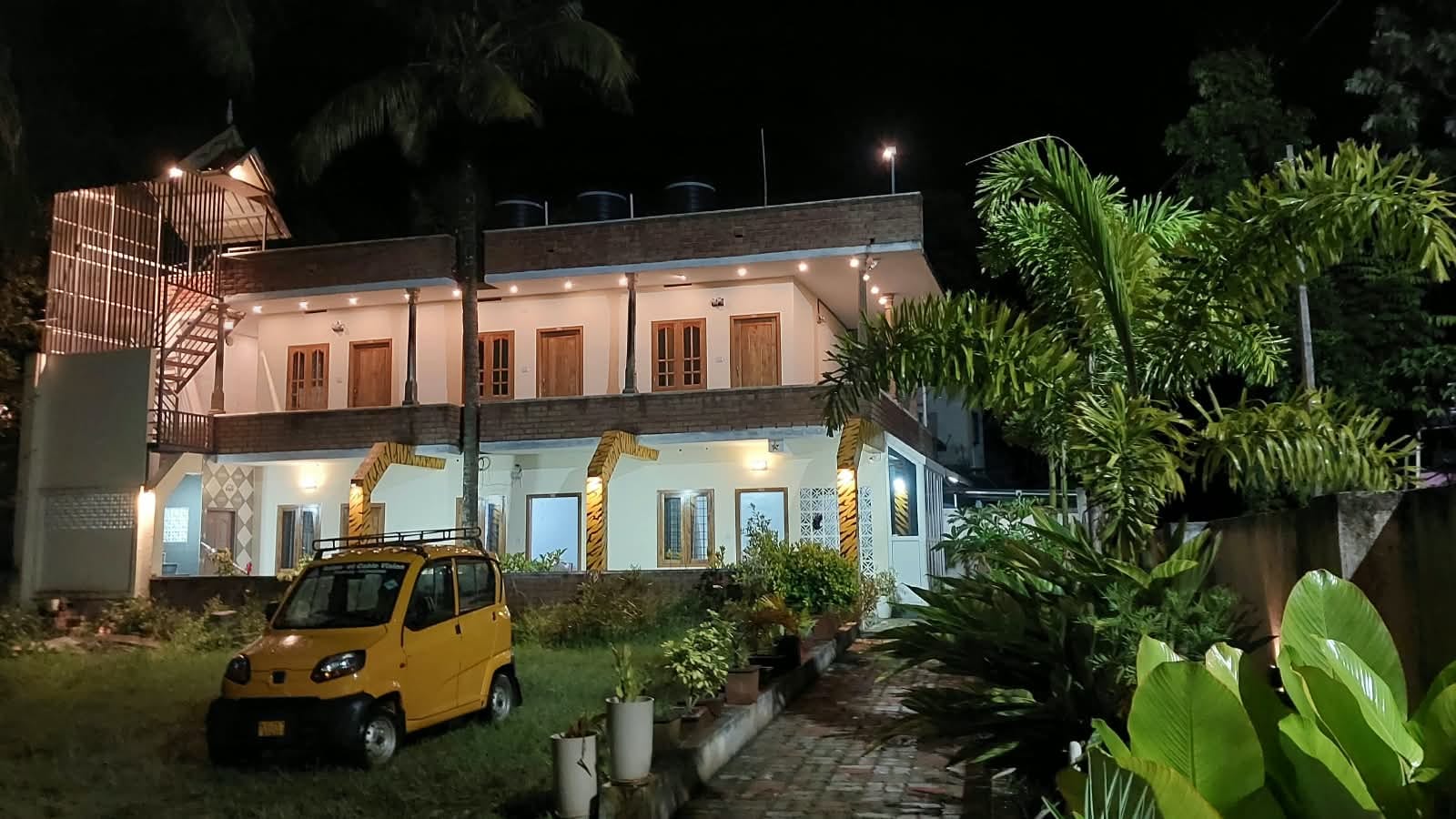 Night view of Euro Inn Homestay with garden plants and a pathway.