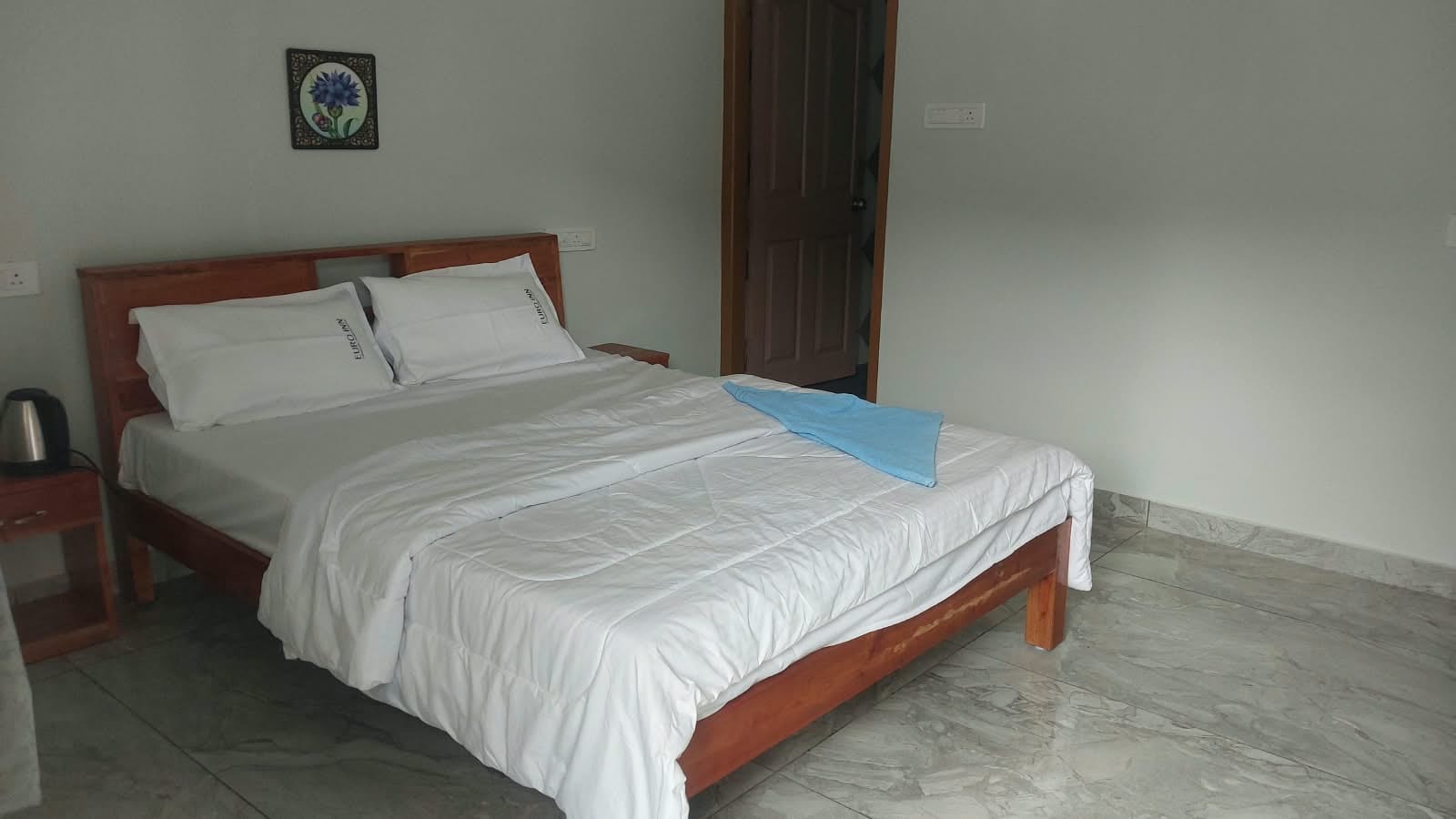 Bedroom with a wooden double bed and blue towel.